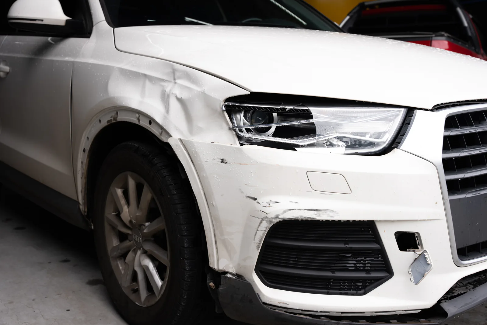 Carro branco com danos de colisão na dianteira em oficina de funilaria e pintura em Arujá